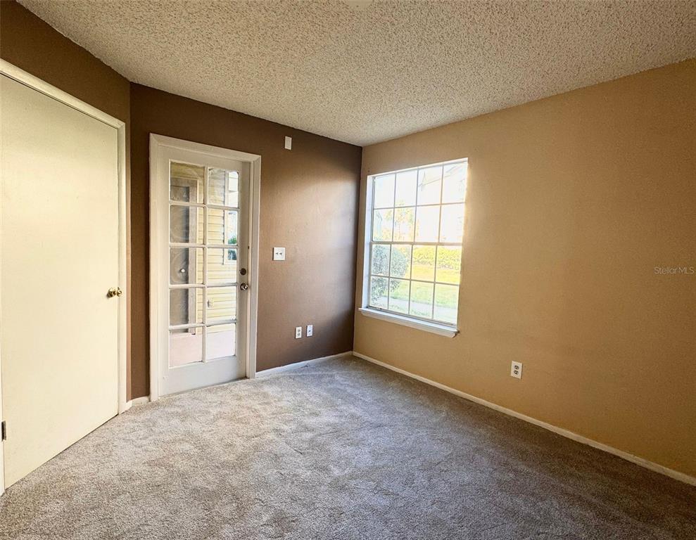 A bedroom features gray carpeting, a glass-paneled door, a window, and two-toned painted walls — 1908 LAKE ATRIUMS CIRCLE UNIT 14, ORLANDO, FL