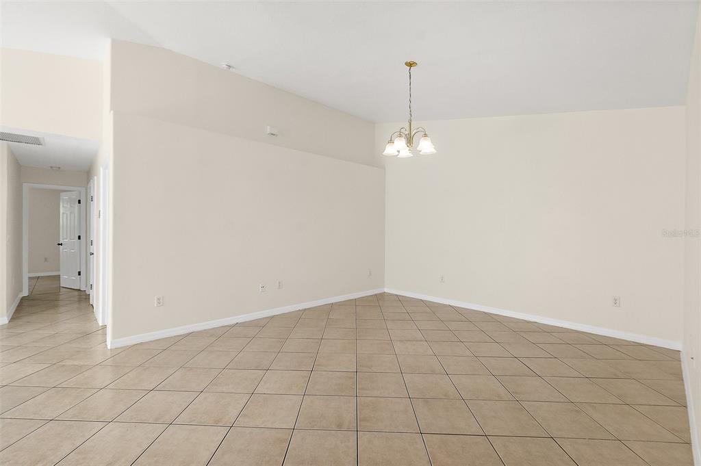 A dining area with beige tile flooring, light-colored walls, and a hanging chandelier — 18 PROSPECT LANE UNIT A & B, PALM COAST, FL