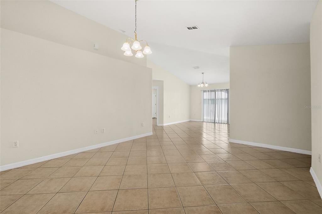 An open-concept living area features beige tile flooring, vaulted ceilings, and two hanging light fixtures — 18 PROSPECT LANE UNIT A & B, PALM COAST, FL