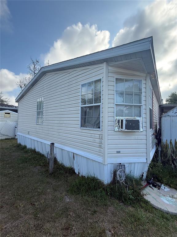 An exterior view of a light-colored mobile home with vinyl siding and a window air conditioner — 4439 AUTUMN PALM DRIVE, ZEPHYRHILLS, FL