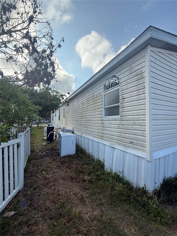 The exterior side of a mobile home features light-colored vinyl siding and a single window — 4439 AUTUMN PALM DRIVE, ZEPHYRHILLS, FL