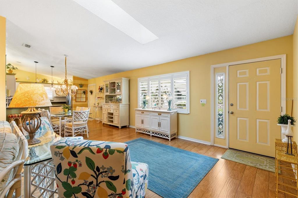 A bright living and dining area features yellow walls, hardwood floors, and a front door — 17990 SE 100TH TERRACE, SUMMERFIELD, FL
