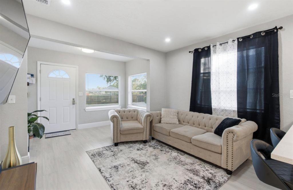 A living room features light wood flooring, a beige tufted sofa, and a matching armchair — 2717 W CHERRY STREET, TAMPA, FL