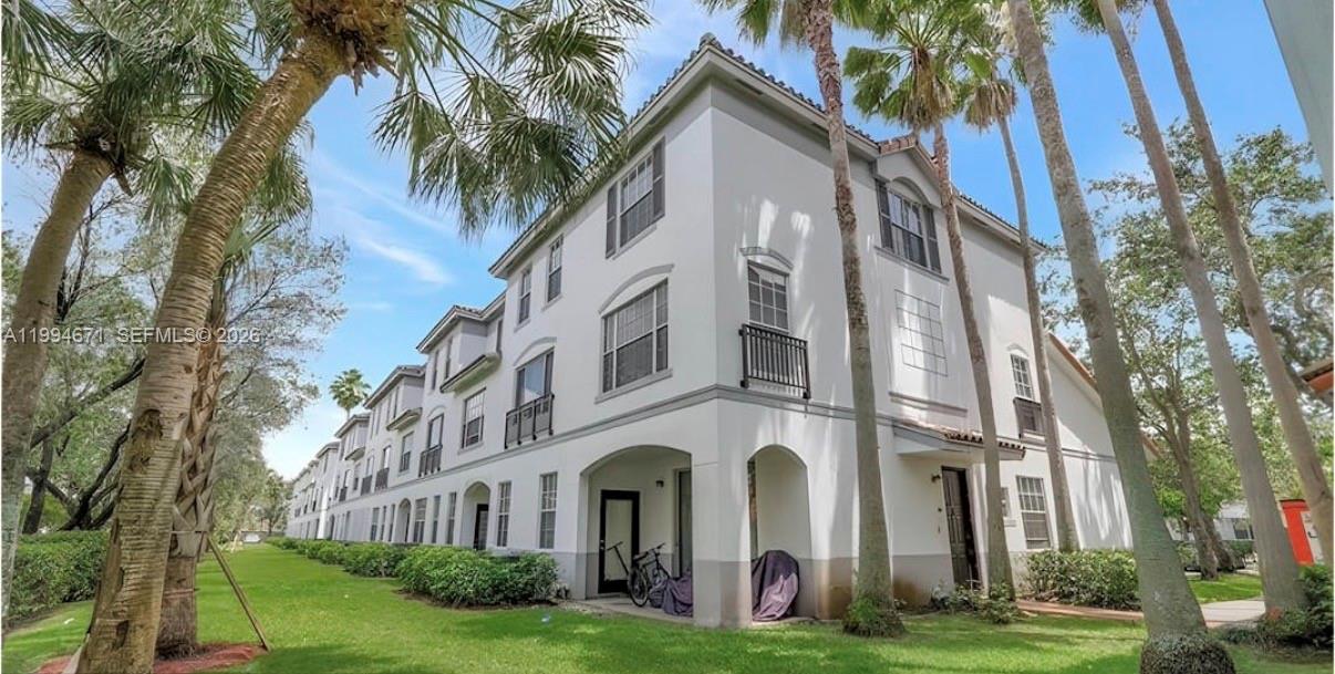 A three-story white apartment building with palm trees and a grassy lawn in front — 705 SW 148th Ave # 202, Sunrise FL 33325, SUNRISE, FL