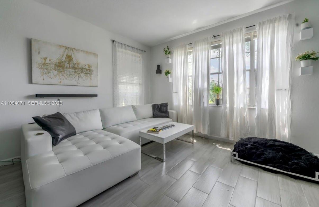 A living room features a white sectional sofa, a coffee table, and light wood-look flooring — 705 SW 148th Ave # 202, Sunrise FL 33325, SUNRISE, FL