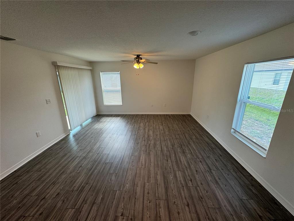 A combined dining and living area features wood-look flooring, a dining table, and a sofa — 233 KENSINGTON VIEW BOULEVARD, WINTER HAVEN, FL