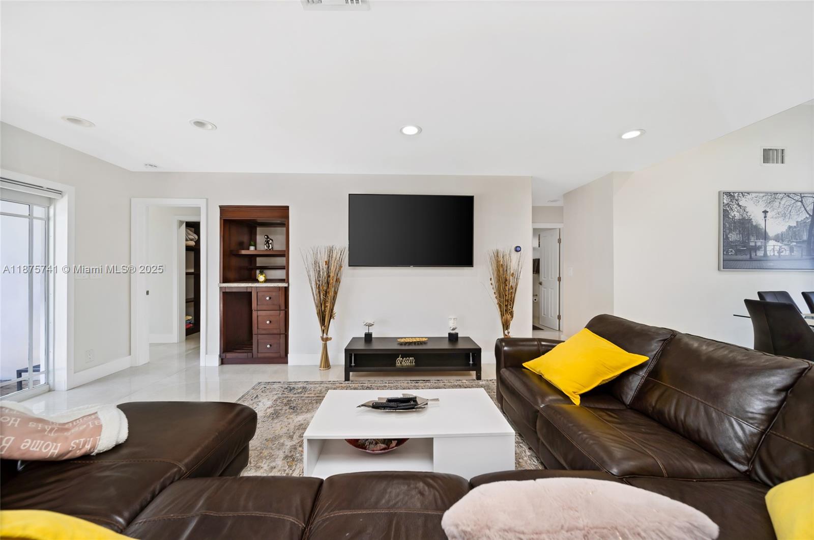A living room features a dark leather sectional, a white coffee table, and a wall-mounted television — 31 SE 12th St, Pompano Beach FL 33060, POMPANO BEACH, FL