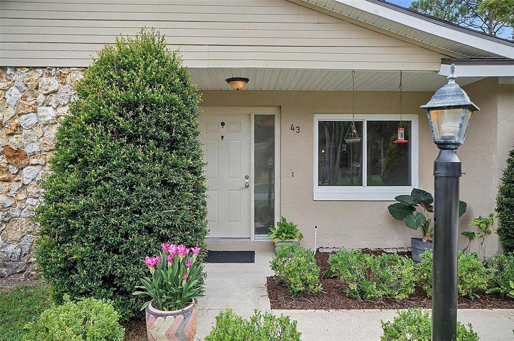The exterior of a house features a stone wall, a front door, and landscaping — 43 BAY SPRING PLACE, PALM COAST, FL