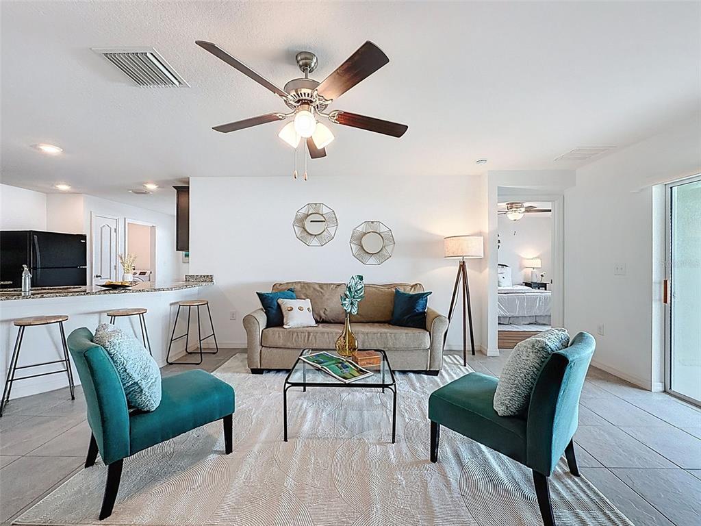 A living room features a beige sofa, two teal armchairs, and a glass coffee table — 12943 IMPATIENS STREET, SPRING HILL, FL