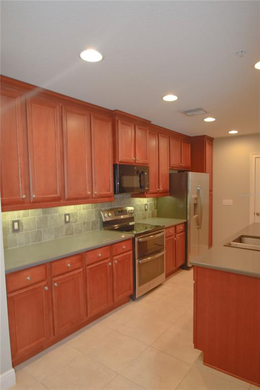A kitchen features cherry wood cabinets, stainless steel appliances, and gray countertops — 1420 LAKE BALDWIN LANE, ORLANDO, FL