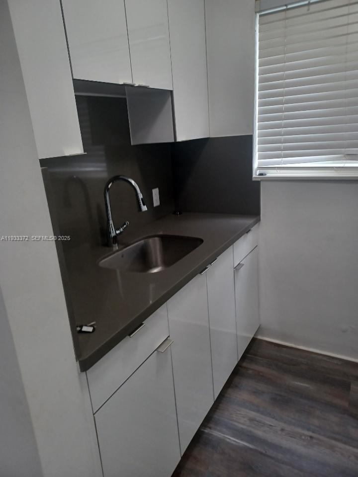 A small kitchen features white cabinets, a dark countertop, and a stainless steel sink — 6950 Byron Ave # 2, Miami Beach FL 33141, MIAMI BEACH, FL