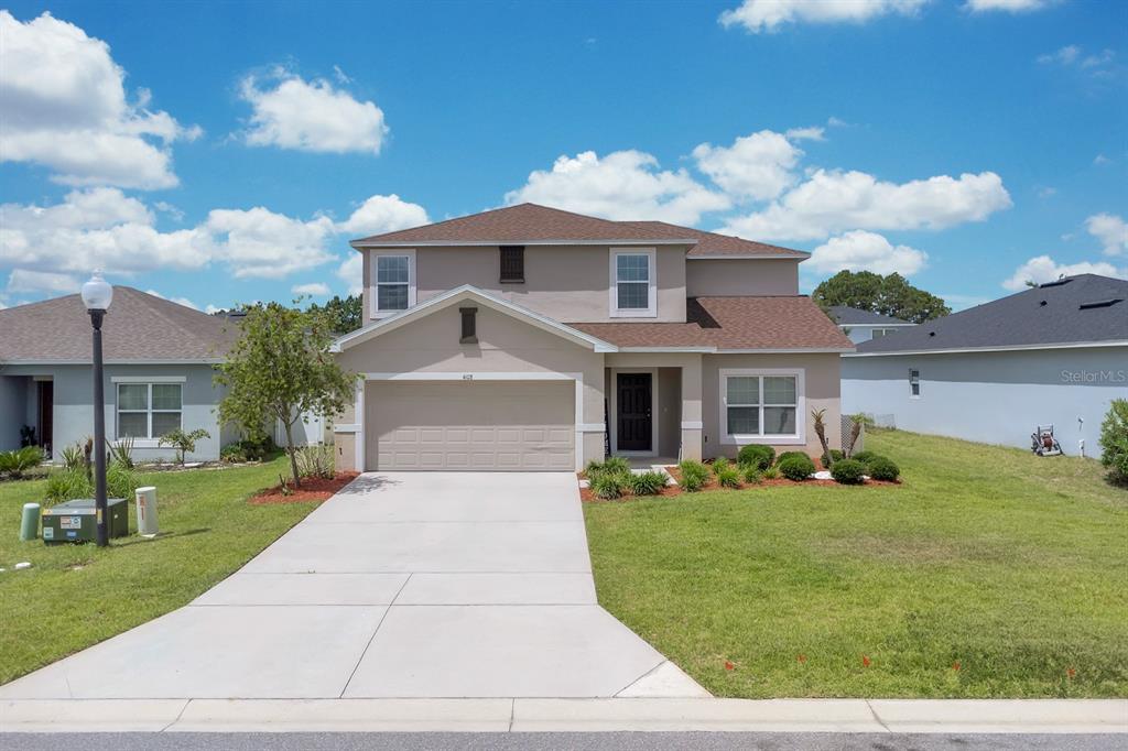 A two-story suburban house with a beige stucco exterior, brown roof, and concrete driveway — 4108 DEERMOSS DRIVE, CLERMONT, FL