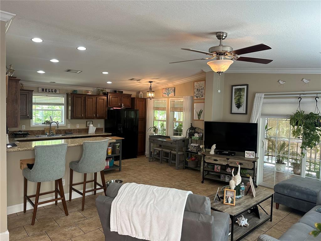 A covered wooden porch features a ceiling fan, a rocking chair, and various potted plants — 462 S DEW PLANT POINT, CRYSTAL RIVER, FL