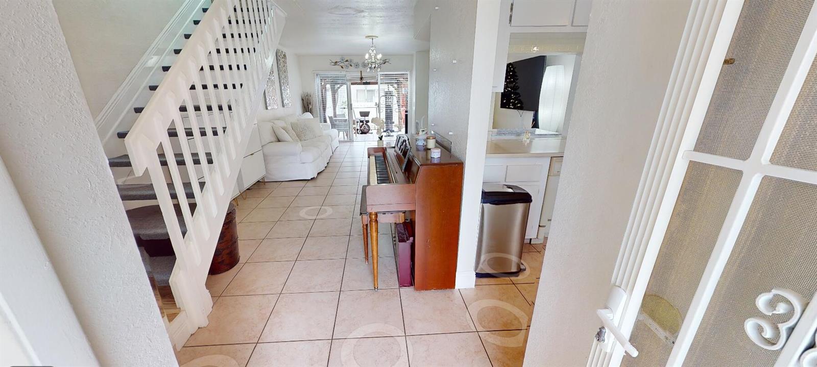 An entryway leads into a living area with tile flooring, a piano, and a staircase — 217 Foxtail Drive # G, FL 33415, FL