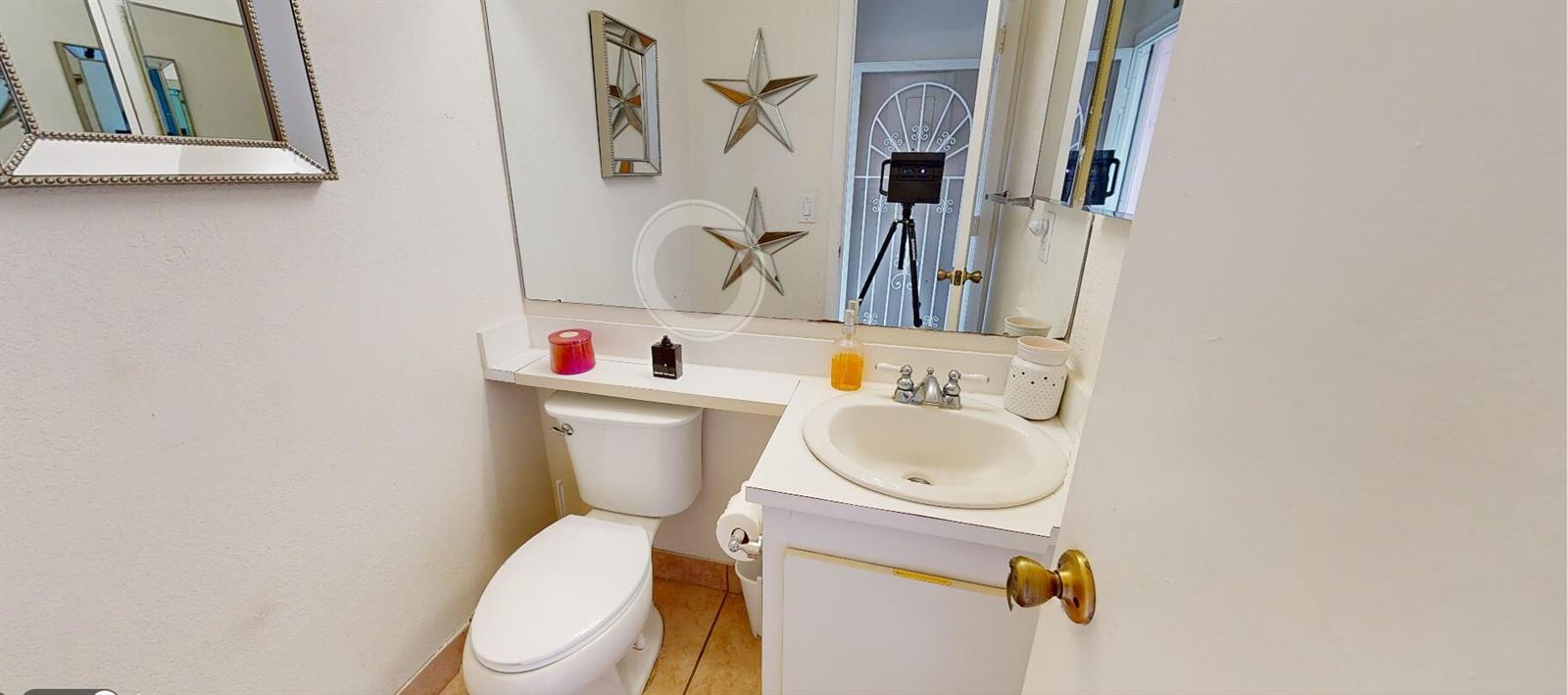 A small bathroom features a white vanity, a toilet, and two decorative stars on the mirror — 217 Foxtail Drive # G, FL 33415, FL