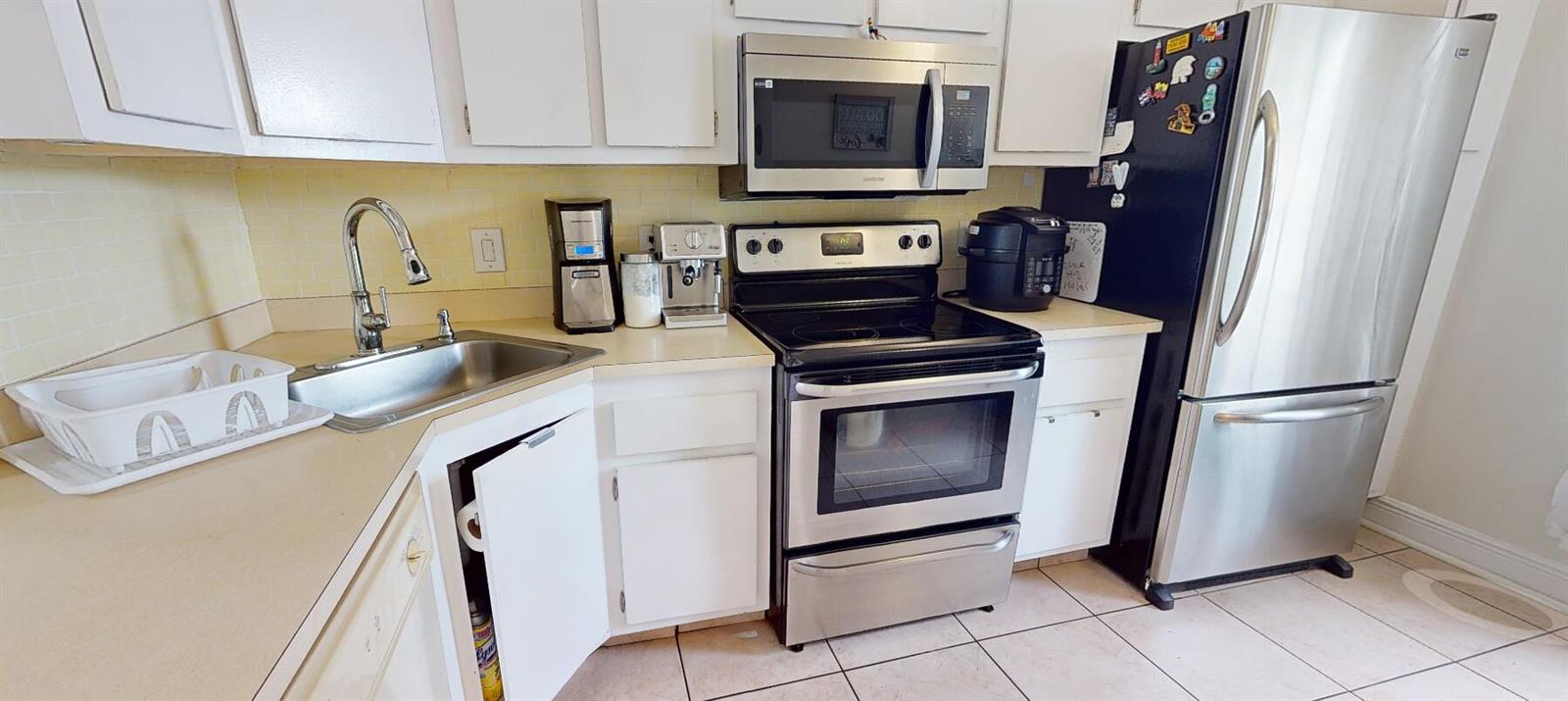 A kitchen features white cabinets, stainless steel appliances, a sink, and light-colored tile flooring — 217 Foxtail Drive # G, FL 33415, FL