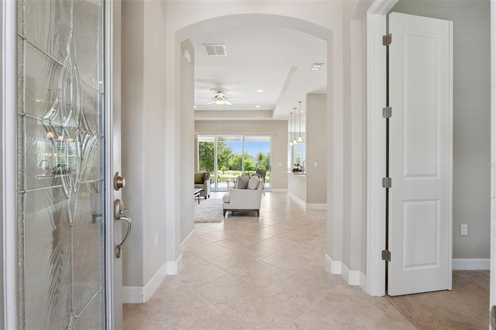 A bright entryway with tile flooring leads into an open-concept living area with backyard views — 1689 VICTORIA GARDENS DRIVE, DELAND, FL