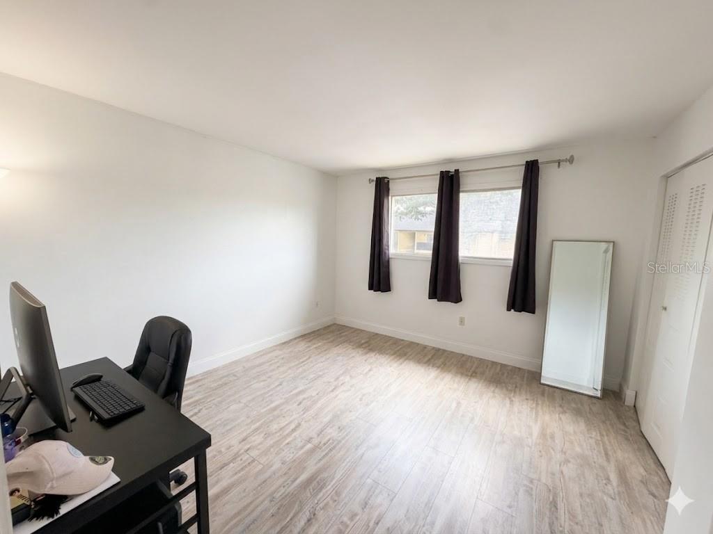 A home office with light wood-look flooring, white walls, a desk, and a floor mirror — 924 LAKE DESTINY ROAD UNIT E, ALTAMONTE SPRINGS, FL