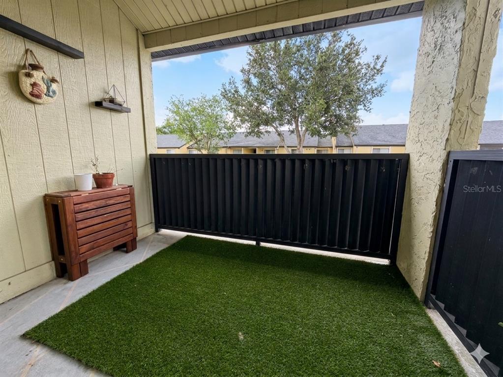 A covered balcony features artificial turf flooring, a wooden storage unit, and a black railing — 924 LAKE DESTINY ROAD UNIT E, ALTAMONTE SPRINGS, FL