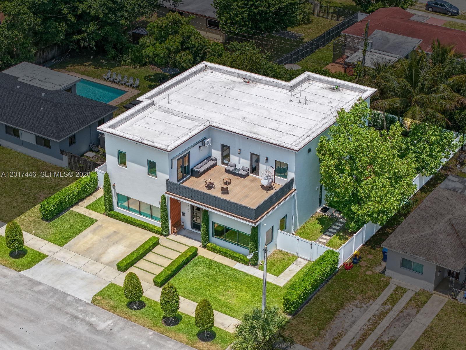 An aerial view shows a two-story white house with a flat roof and wooden deck — 1025 NE 170th Ter, Miami FL 33162, MIAMI, FL