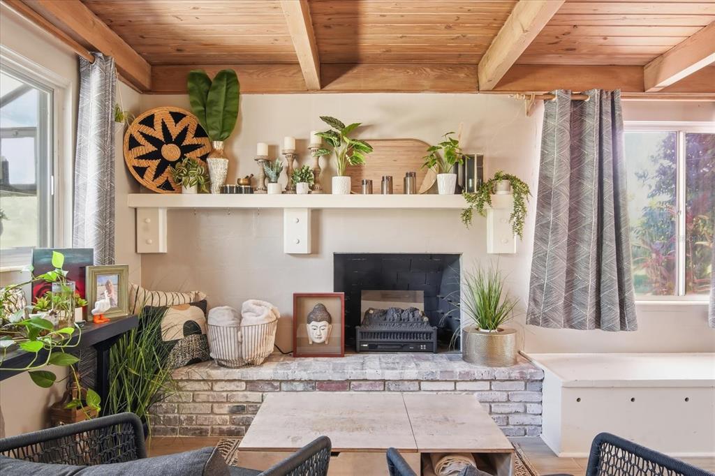 A living room features a brick fireplace, a long mantel with decor, and wood-beamed ceilings — 3307 3RD AVENUE W, BRADENTON, FL
