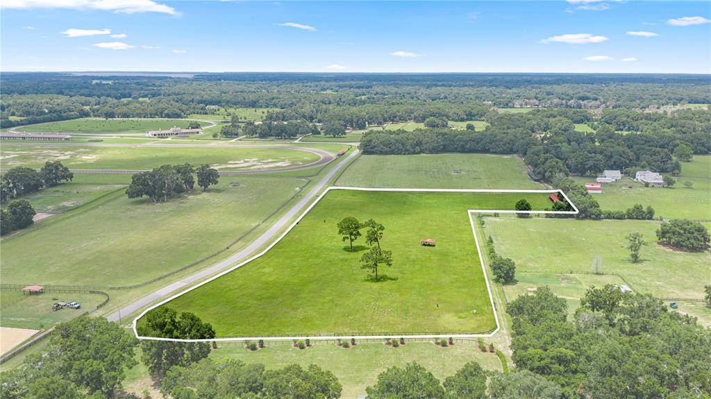 An aerial view shows a large, fenced grassy lot with several trees and a small structure — 15269 NE 15TH COURT, CITRA, FL