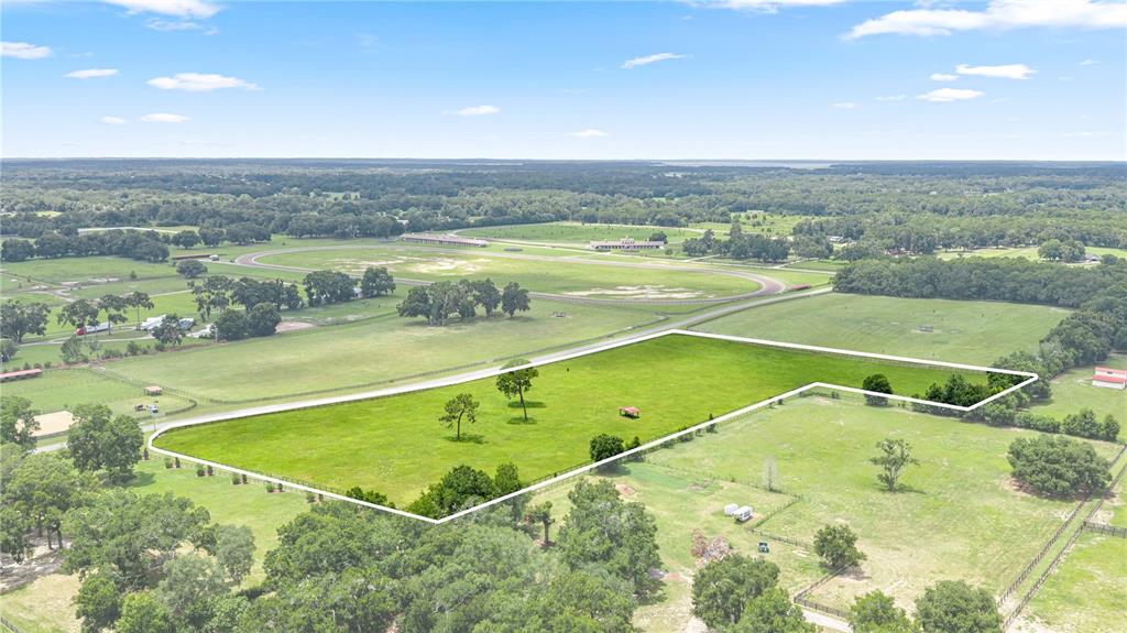 An aerial view shows a large, fenced green pasture with scattered trees and structures — 15269 NE 15TH COURT, CITRA, FL