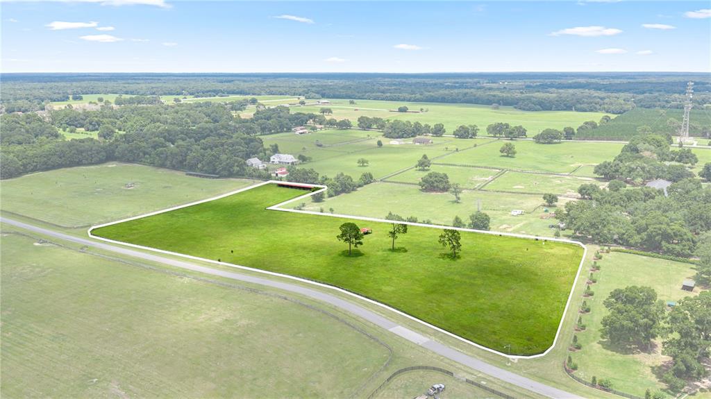 An aerial view shows a fenced, grassy plot of land with several trees — 15269 NE 15TH COURT, CITRA, FL