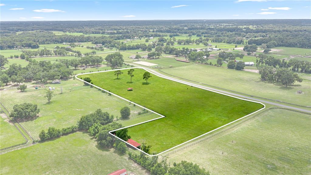 An aerial view shows a large, fenced-in grassy pasture with a small red barn structure — 15269 NE 15TH COURT, CITRA, FL