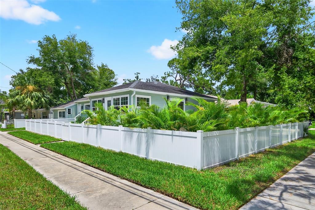 A light green house with a white vinyl fence and palm trees on a corner lot — 1846 3RD STREET S, ST PETERSBURG, FL