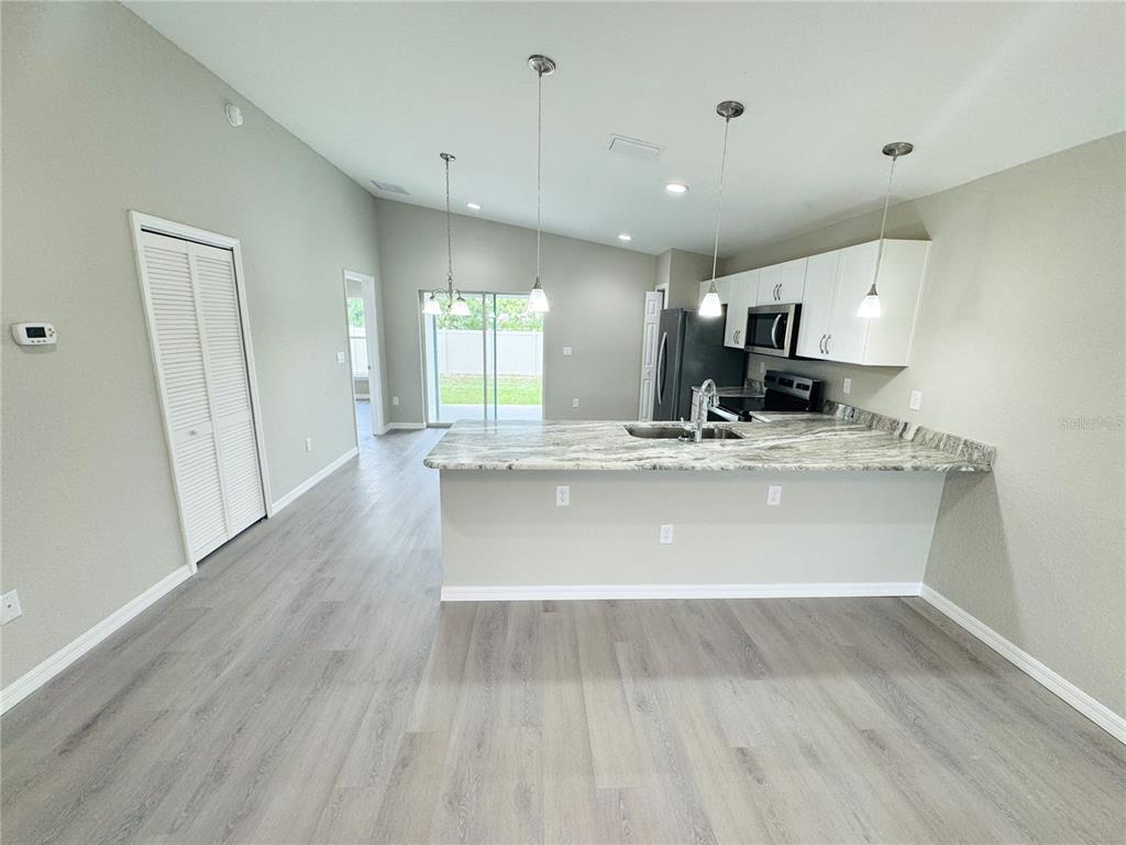 A kitchen with white cabinets, granite countertops, and a breakfast bar overlooks a living area — 6574 SE 108TH STREET, BELLEVIEW, FL