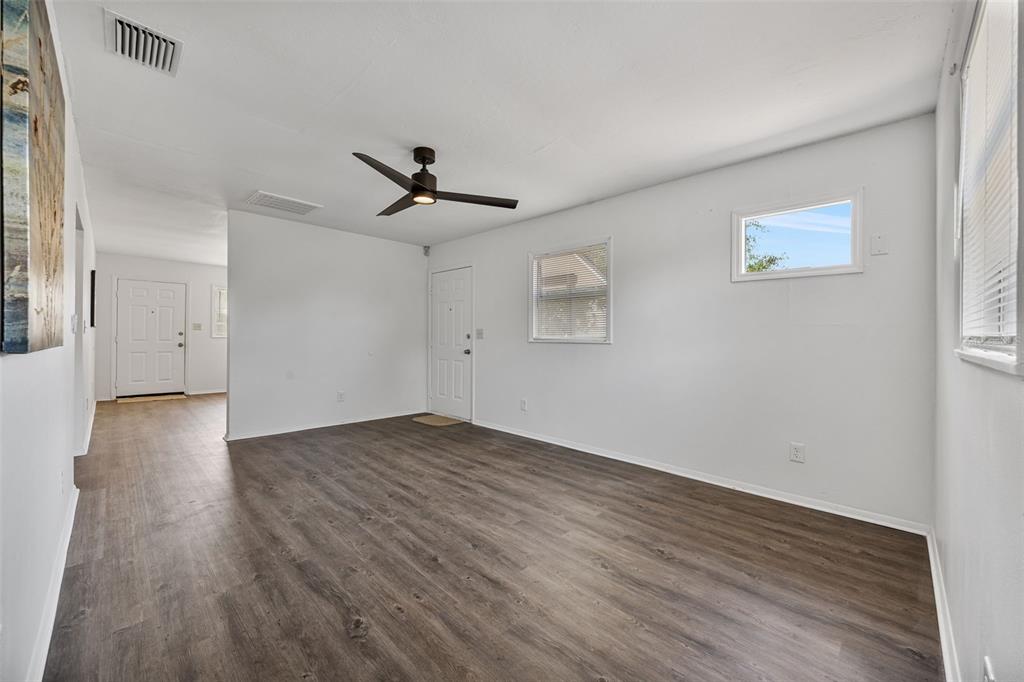 An empty room features dark wood-look flooring, white walls, a ceiling fan, and two doors — 3419 N 54TH STREET, TAMPA, FL