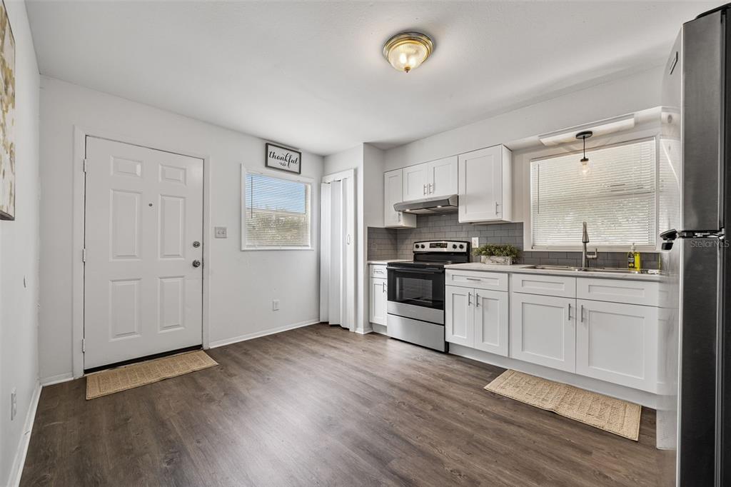 A kitchen with white cabinets, stainless steel appliances, gray subway tile, and wood-look flooring — 3419 N 54TH STREET, TAMPA, FL