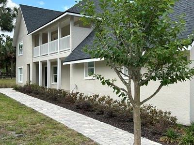 A two-story house with a paved walkway, a covered porch, and a tree in front — 8422 NW 2ND STREET, OCALA, FL