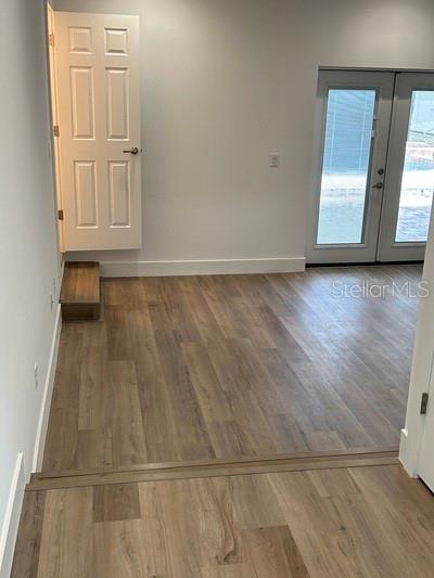 A room with light wood-look flooring, a white interior door, and glass double doors — 8422 NW 2ND STREET, OCALA, FL