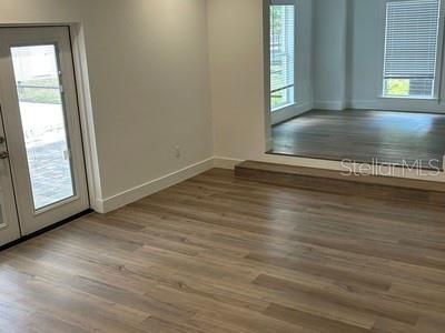 A room with light wood-look flooring features a glass door and a raised platform area — 8422 NW 2ND STREET, OCALA, FL
