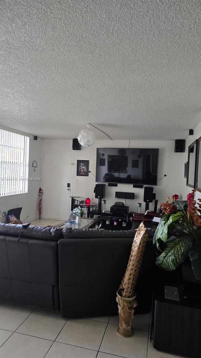 A living room features a large wall-mounted television, surround sound speakers, and a leather sofa — 1748 NW 55th Ave # 101, Lauderhill FL 33313, LAUDERHILL, FL