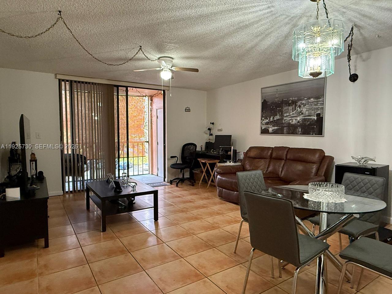 This living and dining area features tile flooring, a brown leather sofa, and a chandelier — 8600 SW 133rd Ave Rd # 310, Miami FL 33183, MIAMI, FL