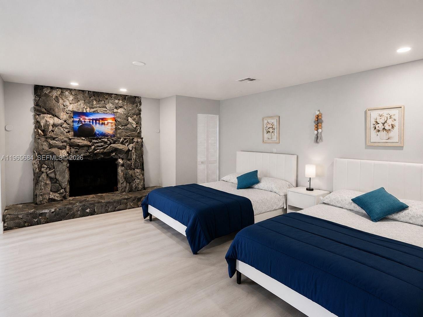 A bedroom features two beds, light wood flooring, and a large stone fireplace — 901 SW 121 AVE, Davie FL 33325, DAVIE, FL