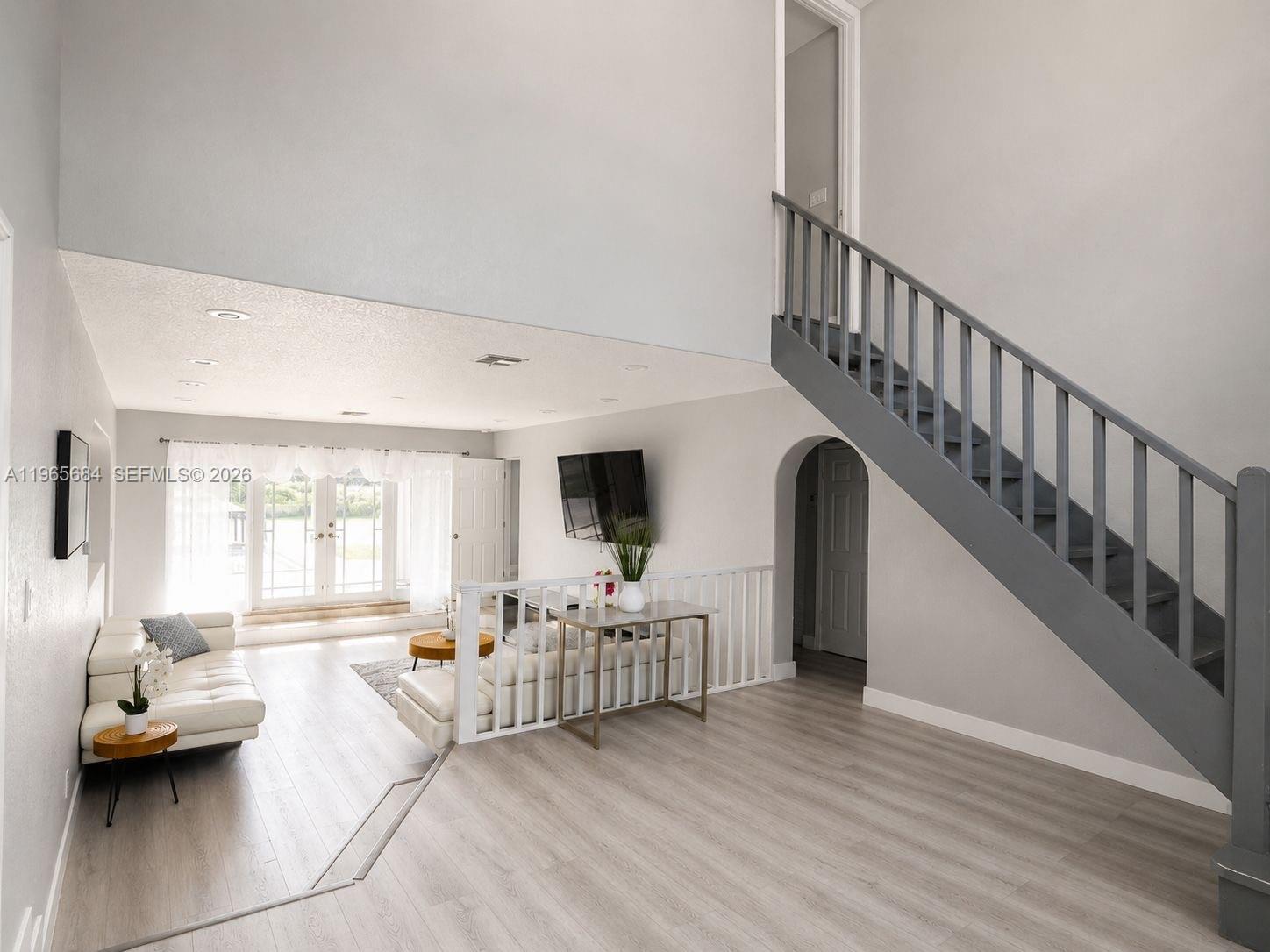 A living room features light wood flooring, a white sofa, and a staircase with railings — 901 SW 121 AVE, Davie FL 33325, DAVIE, FL
