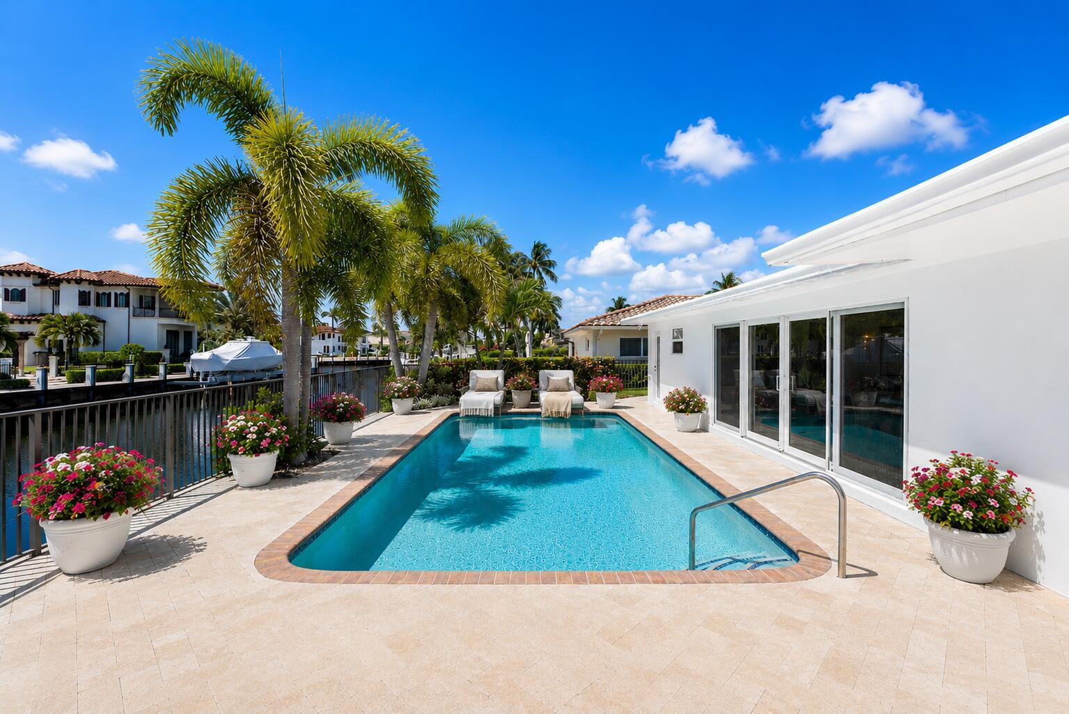 A swimming pool with lounge chairs sits on a patio beside a white house — 4230 NE 24th Avenue, Lighthouse Point FL 33064, LIGHTHOUSE POINT, FL