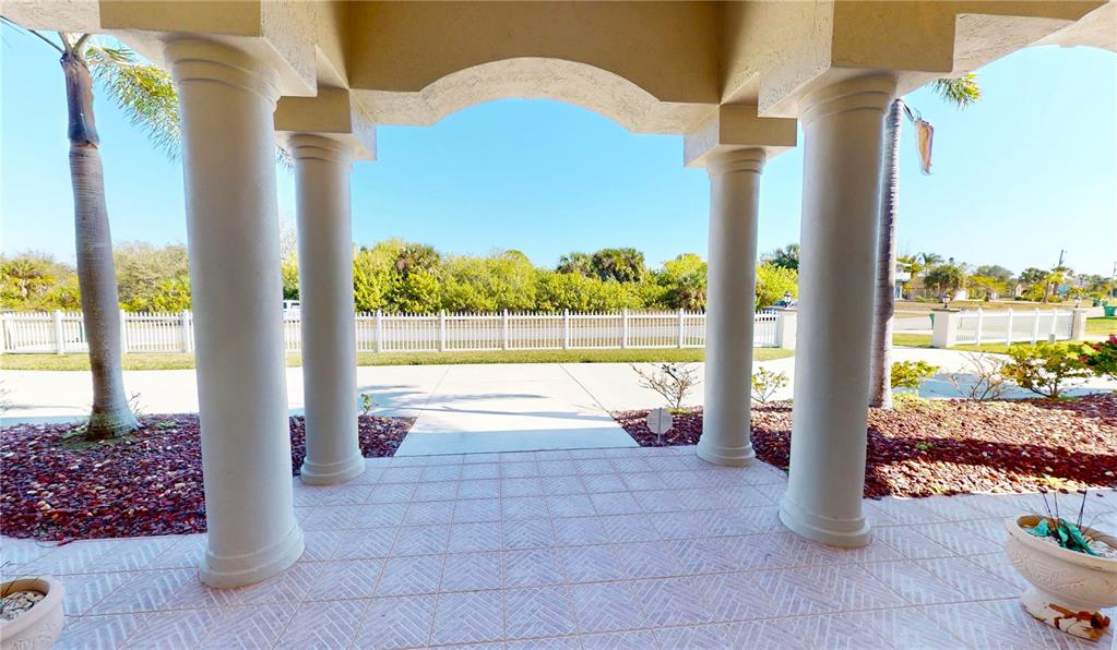 A covered porch with four columns overlooks a paved driveway and a white picket fence — 17449 OHARA DRIVE, PORT CHARLOTTE, FL