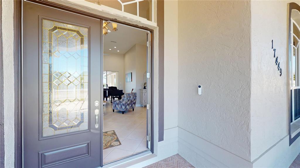 An open front door reveals a tiled entryway and living area with a grand piano — 17449 OHARA DRIVE, PORT CHARLOTTE, FL