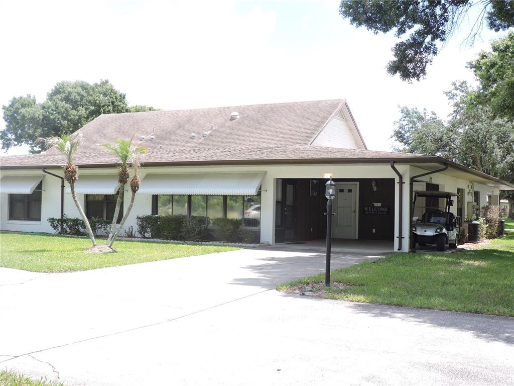 A single-story house with a large carport, white exterior, and a concrete driveway — 281 GENESIS POINTE DRIVE UNIT 8-3, LAKE WALES, FL