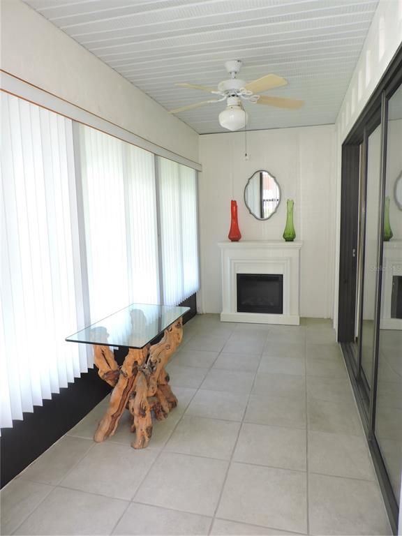A sunroom features a glass-topped driftwood table, a white fireplace, and tile flooring — 281 GENESIS POINTE DRIVE UNIT 8-3, LAKE WALES, FL