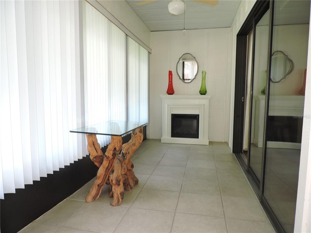 A sunroom features a glass-topped driftwood table, a white fireplace, and light-colored tile flooring — 281 GENESIS POINTE DRIVE UNIT 8-3, LAKE WALES, FL