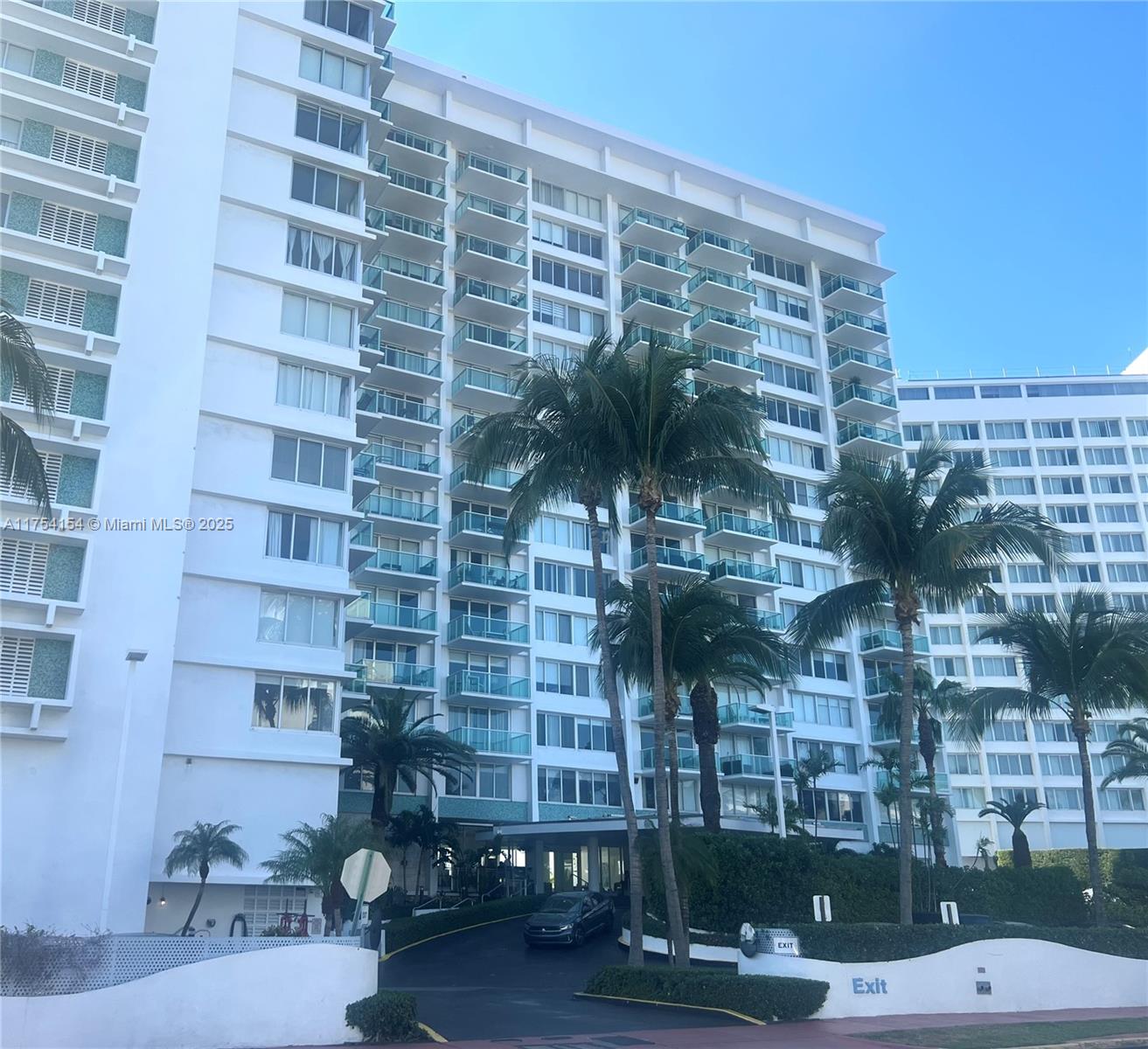The exterior of a multi-story white residential building features balconies and palm trees — 1000 West Ave # 908, Miami Beach FL 33139, MIAMI BEACH, FL
