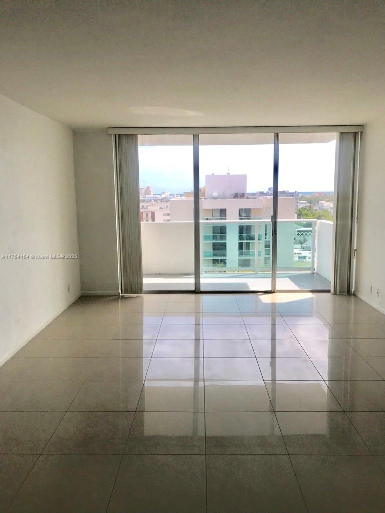 An empty room with large sliding glass doors leading to a balcony and tiled floors — 1000 West Ave # 908, Miami Beach FL 33139, MIAMI BEACH, FL