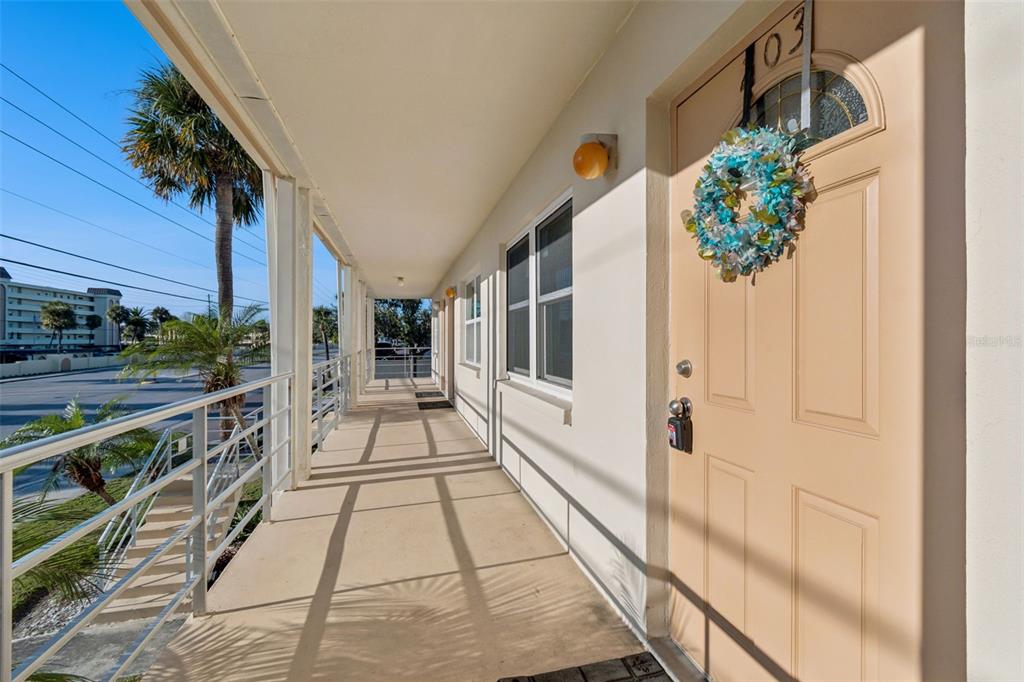 An outdoor walkway leads to a tan door with a wreath and unit number 103 — 4565 DUHME ROAD UNIT 203, ST PETERSBURG, FL
