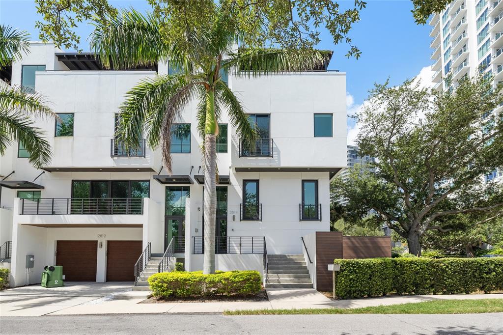 A modern three-story white townhouse with a palm tree, balconies, and two garage doors — 2814 W BARCELONA STREET, TAMPA, FL